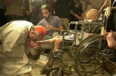 Image of Pope Francis as a Bishop washing the feet of a young, disabled man